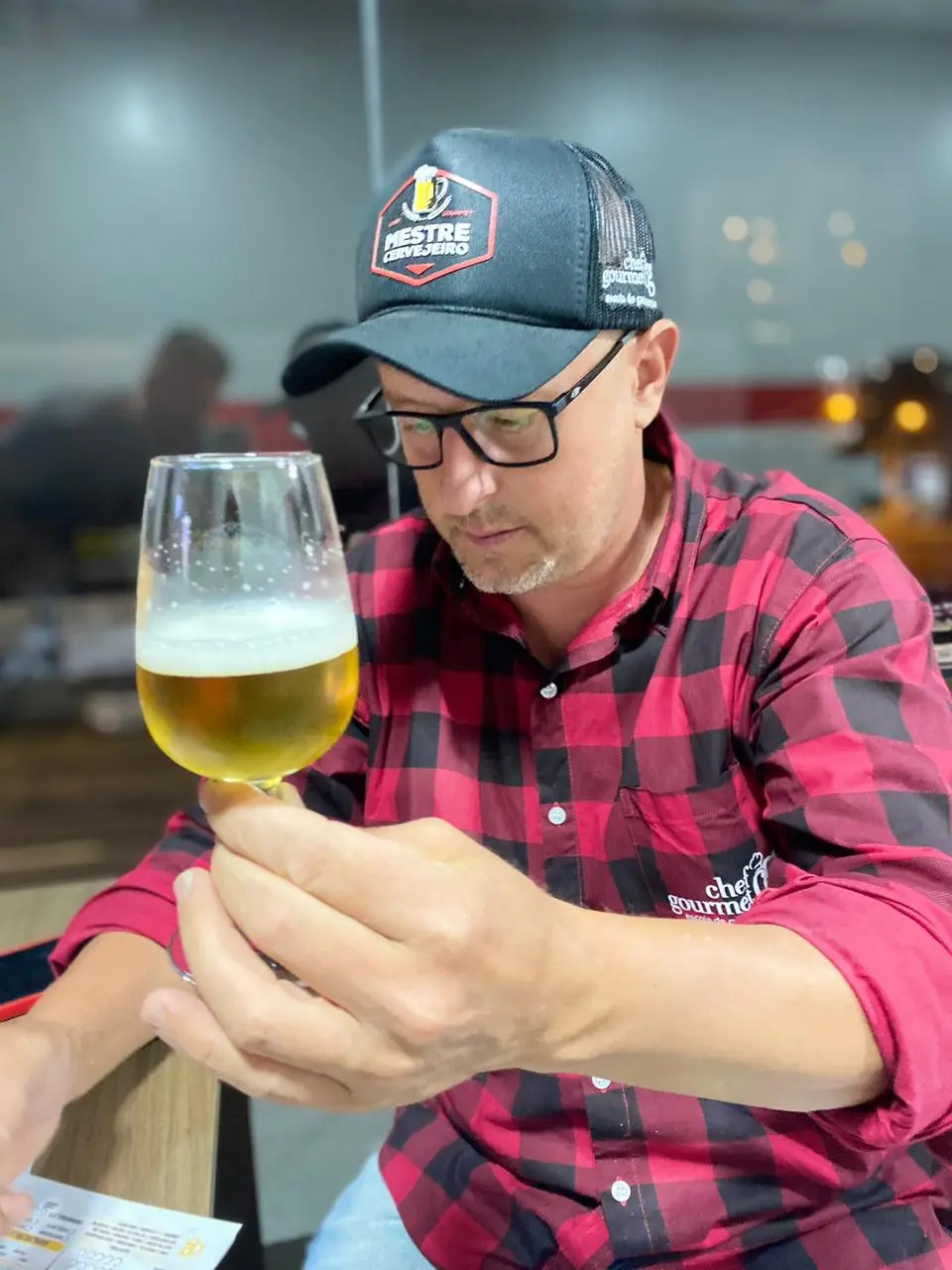 imagem de homem de vermelho e boné segurando um copo de cerveja